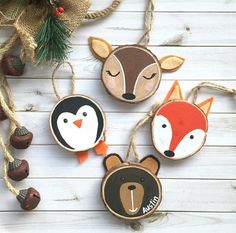 three wooden ornaments with animals on them and pine cones hanging from the strings next to it