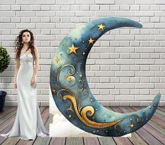 a woman standing next to a statue of a crescent moon with stars and swirls on it