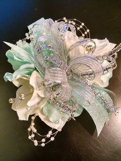 a close up of a flower on a table with brooches and pearls around it