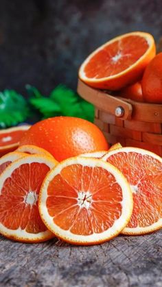 several oranges cut in half sitting next to each other on a wooden table with green leaves