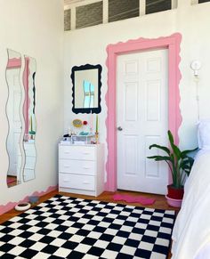 a bedroom decorated in pink, white and black with a checkered rug on the floor