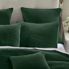 a bed with green comforters and pillows