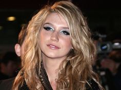 a woman with long blonde hair and blue eyeshadow is posing for the camera