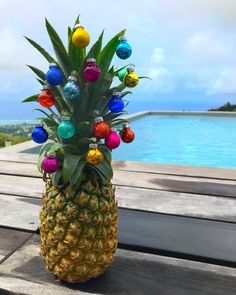 a pineapple with ornaments on it sitting on a wooden table next to the water