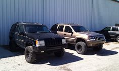 two jeeps are parked next to each other in front of a building with a metal wall