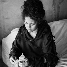 a woman sitting on a bed holding a piece of food in her hand and looking down at it