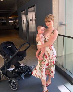 a woman standing next to a baby in a stroller and holding onto her arm