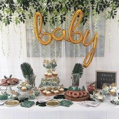 a table topped with lots of desserts and balloons that spell out the word baby