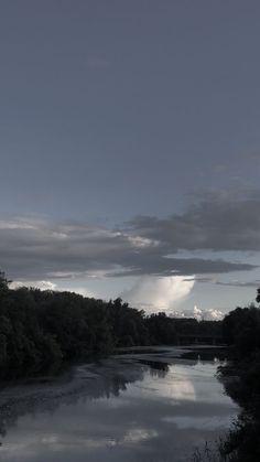 the sky is reflecting in the water and clouds are reflected on the river bank below