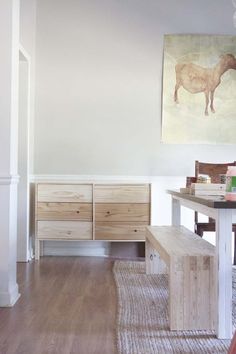 a white room with wooden furniture and a painting hanging on the wall above it's doorway