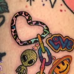 an alien and heart tattoo on the back of a woman's shoulder, with other tattoos