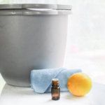 an orange sitting on top of a table next to a glass bottle and a towel