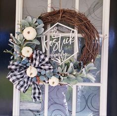 a wreath on the front door with white pumpkins and greenery hanging from it