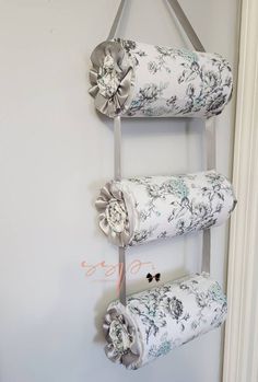 three rolls of toilet paper hanging from a metal holder on a wall with flowers and ribbons