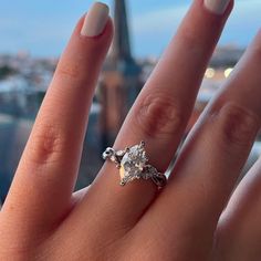 a woman's hand with a ring on it and the eiffel tower in the background