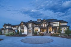 a large house with lots of windows and stonework on the front yard at dusk