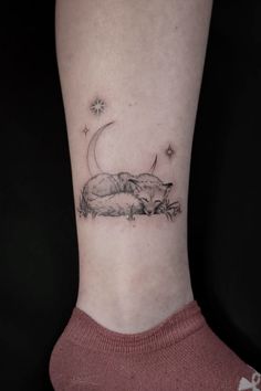 a woman's foot with a small tattoo of a cat sleeping on the grass