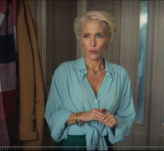 an older woman standing in front of a door with her hands on her hips and looking at the camera