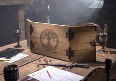 a wooden box sitting on top of a table filled with writing and other items next to a candle