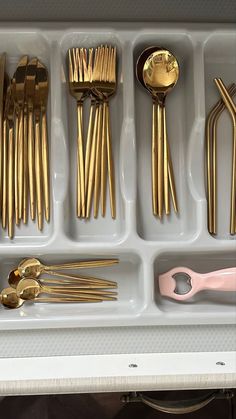 a tray filled with gold colored utensils and spoons