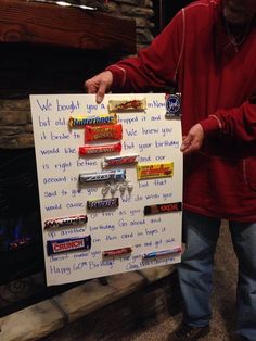 a man holding up a sign with candy bars on it