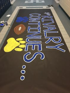 a large sign that is on the floor in a hallway with lockers behind it