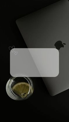 an apple laptop computer sitting on top of a table next to a glass of lemonade