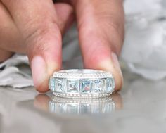 a close up of a person's hand touching a diamond ring