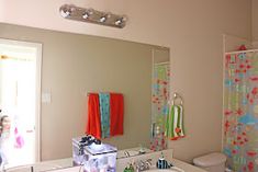 a bathroom with a sink, toilet and shower curtain in the background is a child's play area