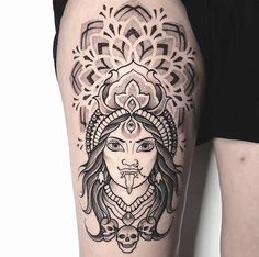 a woman's thigh with an intricate tattoo design on her leg and the head of a demon