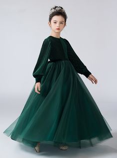 Glisten in sophistication with this exquisite flower girl dress, a masterpiece of elegance and charm. The deep emerald green velvet bodice is intricately designed with soft pleats, offering a touch of vintage allure. Long, balloon sleeves add a dramatic flair, perfectly balanced by the voluminous tulle skirt that sways gracefully with every movement. This dress is not just about aesthetics; it's crafted for comfort, ensuring your flower girl feels as wonderful as she looks. The rich green color is a symbol of timeless beauty, making it a versatile choice for various ceremonies, from weddings to festive gatherings. With a delicate inner lining, the dress provides a soft touch against the skin, preventing any discomfort during long hours of wear. This ensemble, when paired with a sparkling t Green Velvet Dress Short, Flower Girl Velvet Dress, Winter Flower Girl Dresses Velvet, Green Velvet Dress Kids, White Short Party Dress, Piano Dress, Long Sleeve Flower Girl Dress, Velvet Christmas Dress Toddler, Girls Velvet Dress