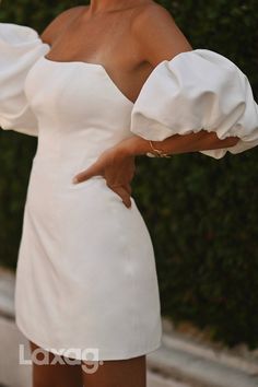 a woman in a white dress posing for the camera with her hand on her hip