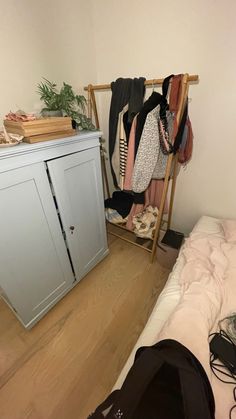 a room with a bed, clothes rack and other items