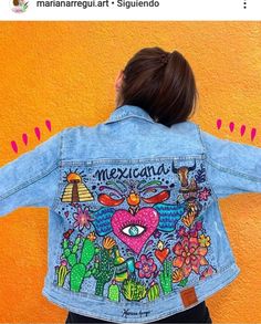 a woman with her back to the camera wearing a jean jacket that has mexican artwork on it