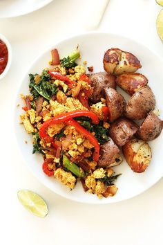 a white plate topped with eggs, potatoes and veggies next to ketchup