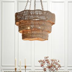 a chandelier hanging over a dining room table with candles and flowers on it