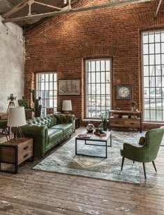 a living room with brick walls and wooden floors, two green couches on top of a rug