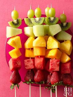 fruit skewers arranged on a pink plate with strawberries and kiwis