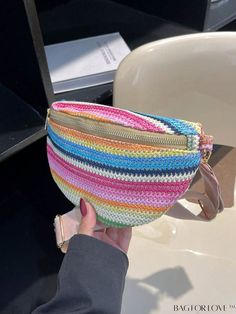 a person holding a multicolored purse in their hand