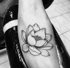 a black and white photo of a lotus flower on the left arm, with its petals still attached