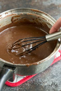 a hand whisking chocolate in a saucepan