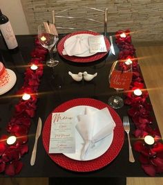 the table is set with red roses and place settings for two people to sit at