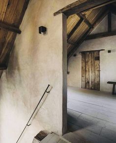 an empty room with wooden beams and exposed ceilinging, along with stone steps leading up to the second floor