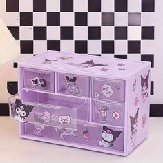 a purple drawer with many drawers and stickers on the front, sitting next to a black and white checkered wall