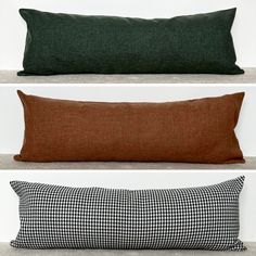 three different types of pillows sitting on the floor in front of each other, one black and white checkered pillow