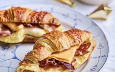 two croissants on a plate with bacon and cheese