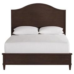 a bed with white pillows and brown headboard