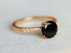 a gold ring with a black stone and white stones on the side, sitting on a table