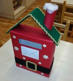 a red mail box with a santa hat on top and an envelope in the middle