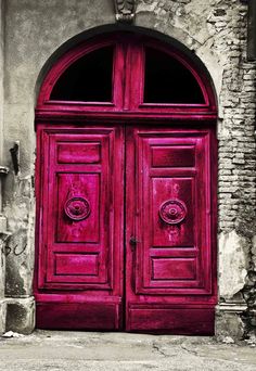 an old red door is open in front of a brick building with arched doorways